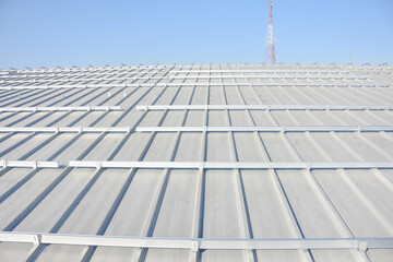 sloped metal roof. The roof has a series of parallel ridges and is equipped with numerous mounting brackets, likely for the installation of solar panels or another type of equipment