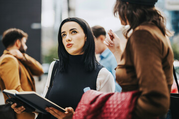 A group of business people engage in a conversation outdoors in a city environment, reflecting teamwork and collaboration. The image captures a lively and dynamic urban business atmosphere.
