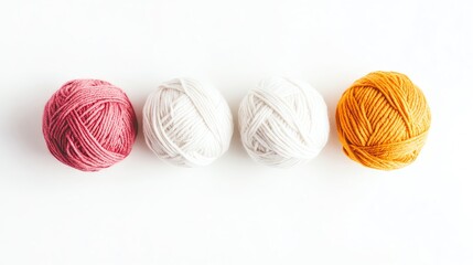 Four colorful yarn balls in pink, white, and yellow are arranged neatly on a white background, showcasing their texture and vibrant hues.