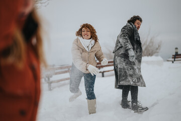 Friends having fun outdoors throwing snowballs in a playful winter scene, depicting joyful...