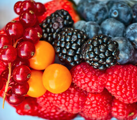 Macro photo of a delicious natural dessert and great ingredients for a fruit salad. Fruits and berries close-up. Raspberries, blueberries, blackberries, currants, strawberries.