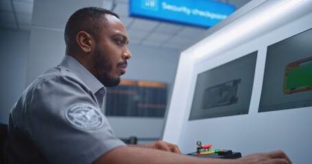 Airport Terminal: African American Security Officer Monitors Baggage Screening Moving on Conveyor...