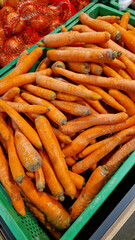 Washed ripe carrots on sale in the store. Carrots close-up. Vegetable crop. A pile of washed carrots in a plastic box, selective focus. Vegetables in the supermarket close-up