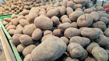 Selling potatoes. Close-up of potatoes at a market or store counter. Food product, harvest. A pile of potatoes in a supermarket, selective focus