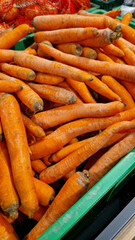 Washed ripe carrots on sale in the store. Carrots close-up. Vegetable crop. A pile of washed carrots in a plastic box, selective focus. Vegetables in the supermarket close-up