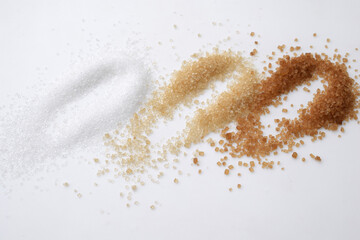 Sugar of more colors and different crystal size on a white background