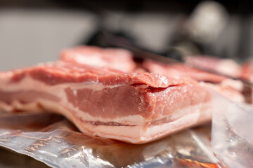 A piece of meat is on a table. The meat is cut in half. The meat is on a plastic wrap