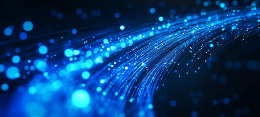 Obraz premium Blue glowing fiber-optic cables with light particles moving rapidly on a dark background