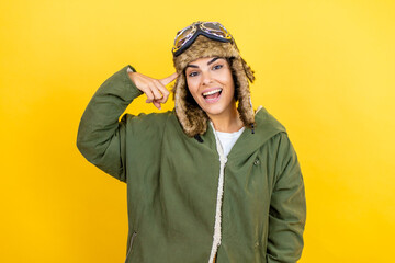 Young beautiful aviator woman wearing vintage pilot helmet with glasses and jacket over yellow background smiling and thinking with her fingers on her head that she has an idea.