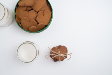 Heart shaped cookies and a glass of milk on a light background. Delicious snack and pastry