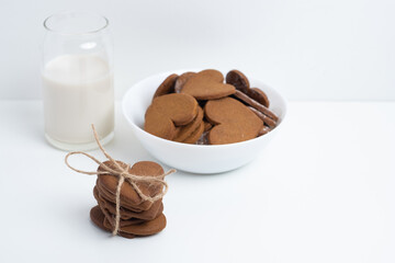 Heart shaped cookies and a glass of milk on a light background. Delicious snack and pastry