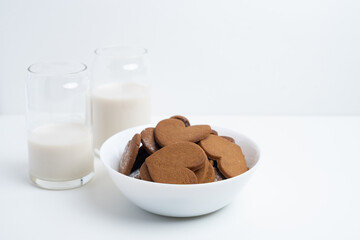 Heart shaped cookies and a glass of milk on a light background. Delicious snack and pastry