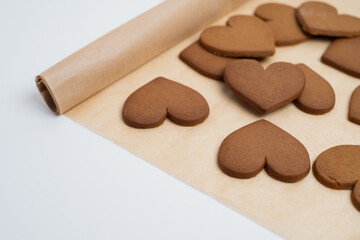 Gingerbread heart cookies on parchment paper. Delicious baking