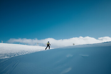An individual skiing on a snowy mountain under a clear blue sky, embracing the winter sport and the beauty of the pristine alpine landscape.