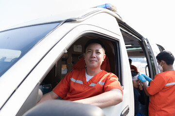 Asian male ambulance staff member in ambulance car. Wearing ambulance uniform of paramedics talking by portable radio during sitting with paramedics giving injured person first aid © amorn