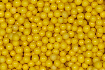 Vibrant Yellow Sugar Sprinkles Background: Macro Photography of Decorative Candy Pearls Used for Cake Decoration and Confectionery Garnish