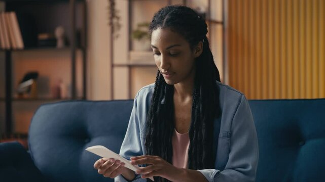 Young woman opens an envelope with a college acceptance letter, feeling happy