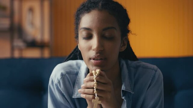 Portrait of a young African American woman praying and opening her eyes in hope