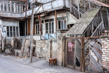 Abgenutztes Gebäude mit Treppe und verlassenem Stuhl in Tbilissi