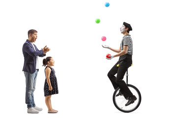 Father and daughter watching a juggler on a mono cycle