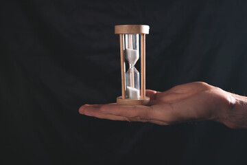 hourglass with hand on a dark background