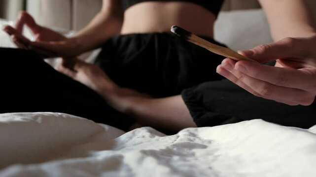 Person in the lotus pose holding wooden palo santo stick in the hand. Aroma therapy.	