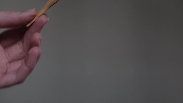 Wooden palo santo stick in the hand on the gray background. Aroma therapy.	