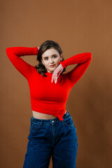 A fashionable young woman in a bold red top and wide-leg denim jeans strikes a dynamic and artistic...