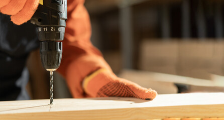 Close-up of female carpenter working with drill at carpentry workshop
