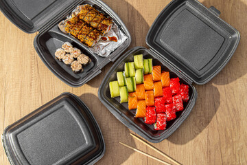 Three boxes of sushi sets on wooden table. Top view. Asian food delivery at home