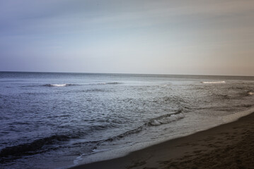 Calm beach on the Baltic Sea in the warm light of sunset. Gentle waves, sandy coastline and subtle atmosphere of relaxation. Perfect image for themes related to nature, travel, and holidays.