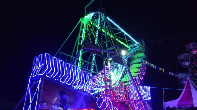 Kora-kora ride or swing boat with colorful lights at carnival parade or night market