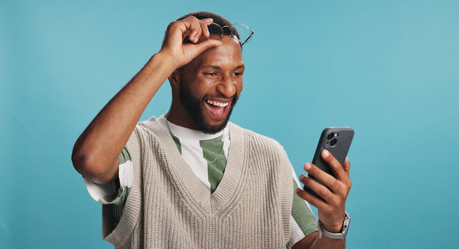 Bonus, phone and surprise with black man in studio isolated on blue background for alert or announcement. Excited, reaction and wow with winner African person reading text message for promotion