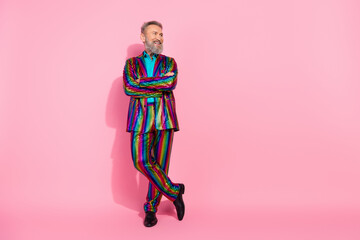 Eccentric elderly man posing in vibrant striped suit against a bright pink background