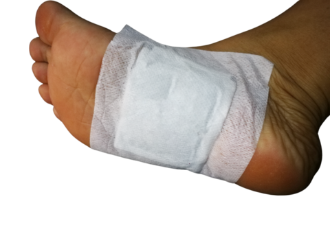 Close-up of foot covered with gauze or pain relief patch on the sole of the foot. Isolated on backgrond.