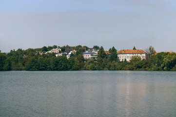Obraz premium The level of a water lake with the opposite shore. Trees and nature on the opposite shore of the lake. Houses on the other side of the lake. Nature, natural lake, water level.