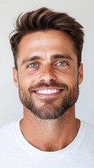 Fototapeta premium Portrait of a smiling man with freckles and light brown hair, wearing a plain white shirt against a neutral background. The image is well lit and shows a natural, friendly expression.