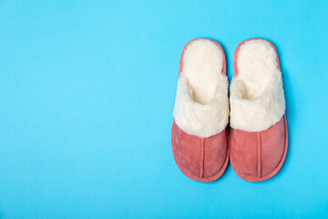 Soft slippers on a bright colored background, close-up. House slippers. Comfortable shoes for home. Foot care concept. Home comfort. Space for text. Copy space.