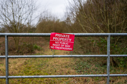 Private property sign on a gate blocking access to a rural path.