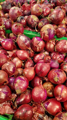 Red onion close-up in supermarket. Lots of red onions in plastic green box on market stall. Onions in green plastic box at farmers market. Onions for sale in store