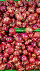 Red onion close-up in supermarket. Lots of red onions in plastic green box on market stall. Onions in green plastic box at farmers market. Onions for sale in store