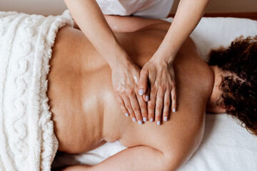 Obese middle-aged woman receives a special body massage intended for weight reduction and correction of bad posture. Modern weight loss physical therapy and beauty spa concept.