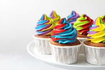 Tasty cupcakes with colorful cream on white background, closeup. Space for text