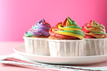Delicious cupcakes with colorful cream on pink table, closeup