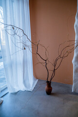 On the gray concrete floor there is a clay vase with a decorative branch