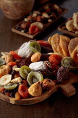 Mix of dried tropical fruits, nuts, and raisins on a wooden table.