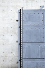 close up of Metal door surface with rivets attach on Grey Polished concrete Grunge textured wall background, Rivets on gray metal.