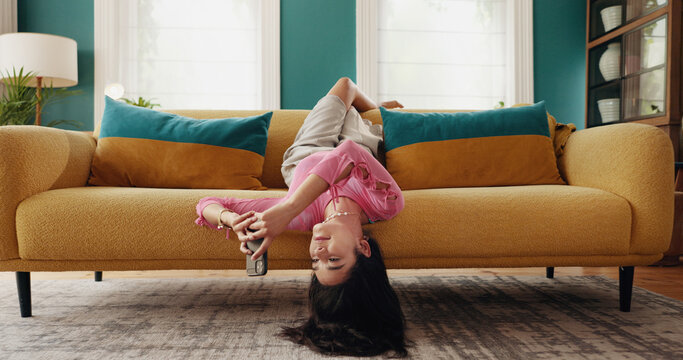 Phone, upside down and woman relax in home, reading text and post on social media profile online. Mobile, sofa and girl on chat app for communication, check notification and message on internet forum