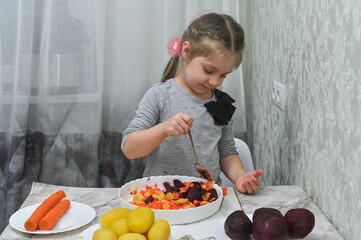 A little girl makes a salad of vegetables.