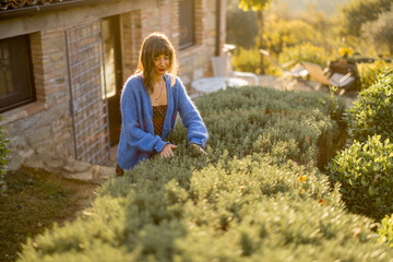 A woman enjoying a serene moment in a rustic garden, surrounded by lush greenery and a charming...